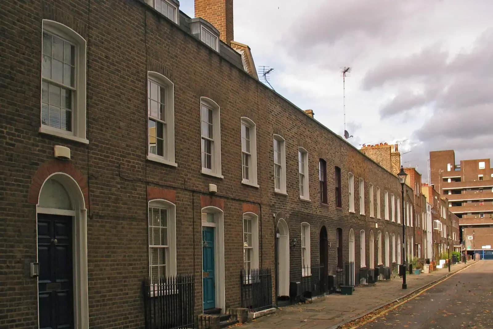 A terrace of dark brick Georgian houses with arched doorways and iron railings along Wynyatt Street, with trees and a lamp post