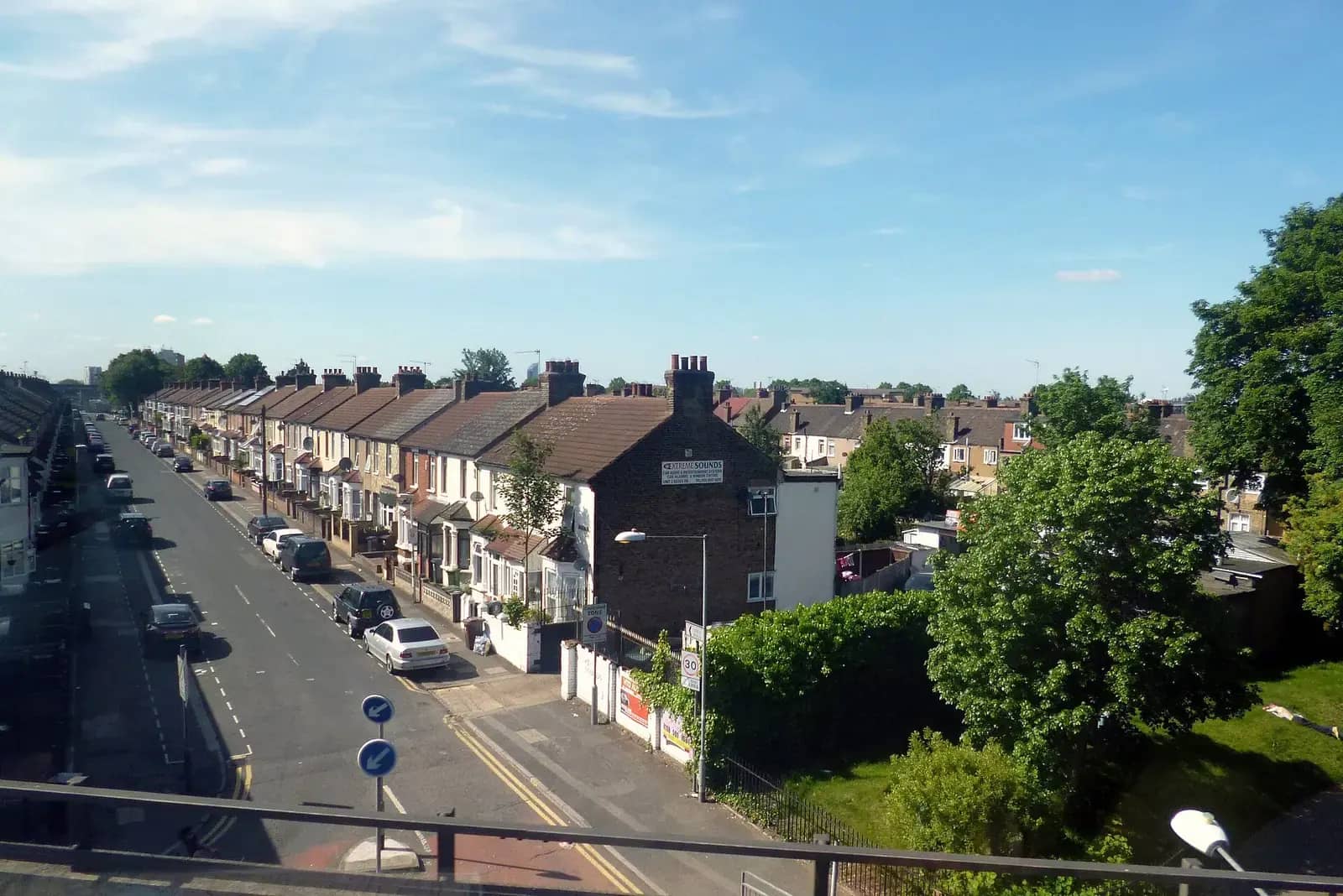 Long straight road of brick terraced houses in Barking seen from a footbridge on a sunny day
