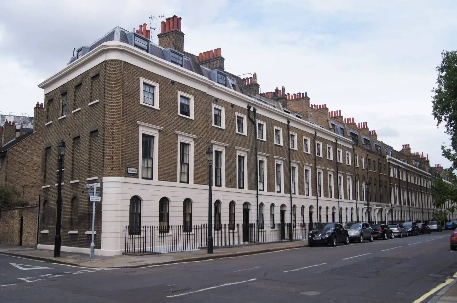 Long terrace of Georgian town houses with white stucco ground floor and brown brick above, on Trinity Street in Southwark