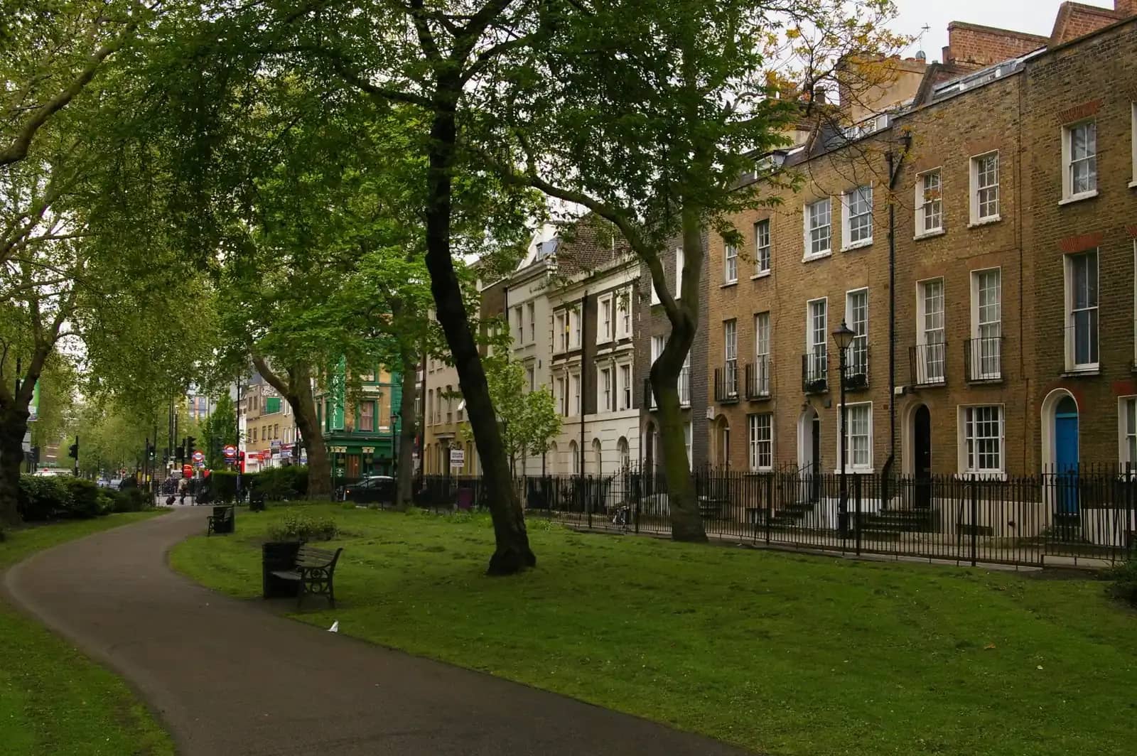 Georgian terrace of brown brick houses facing a leafy green on Paradise Row in Bethnal Green, a path curving through the park