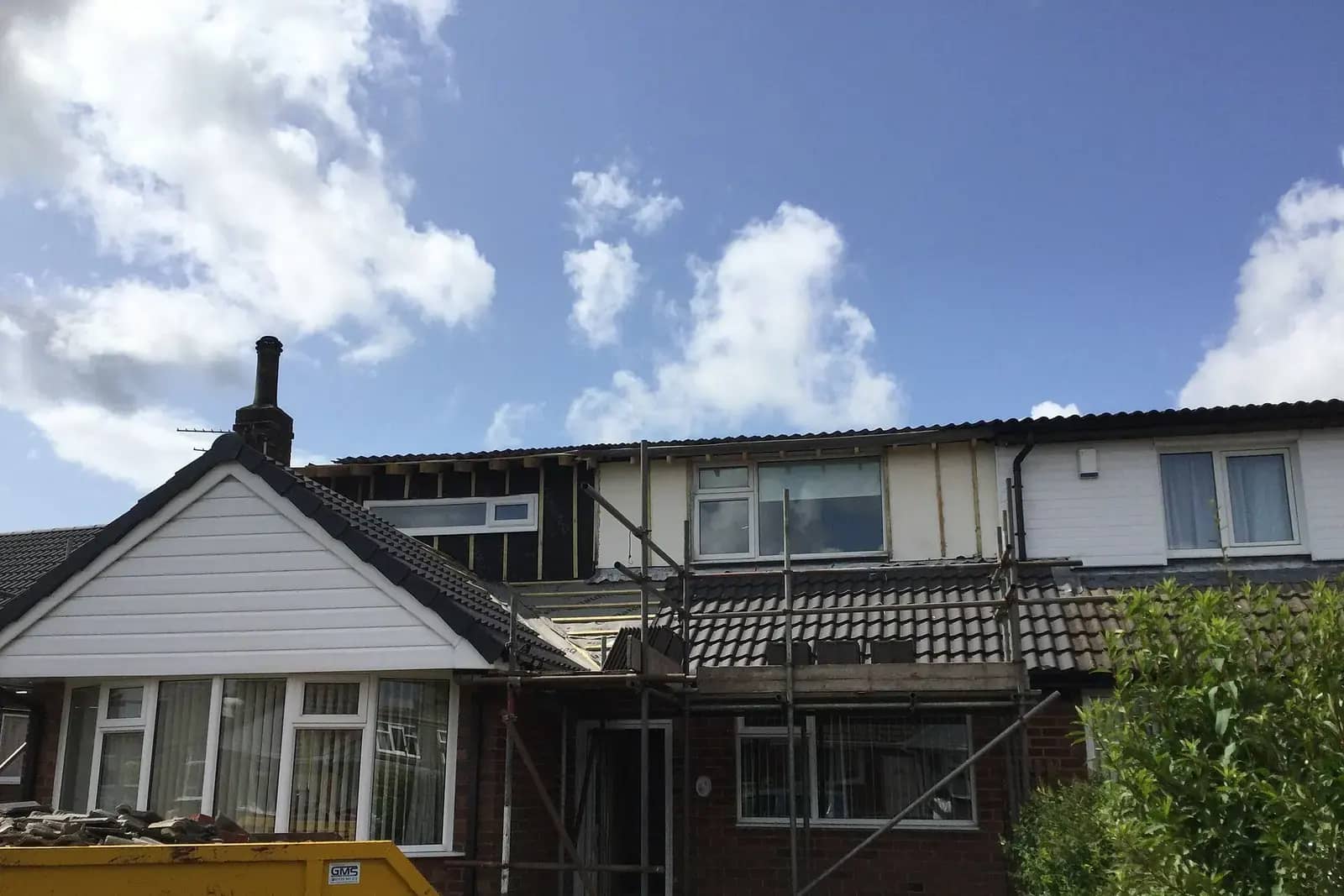 Single-storey house with a new front dormer being built on its roof, scaffolding and black membrane on the new walls