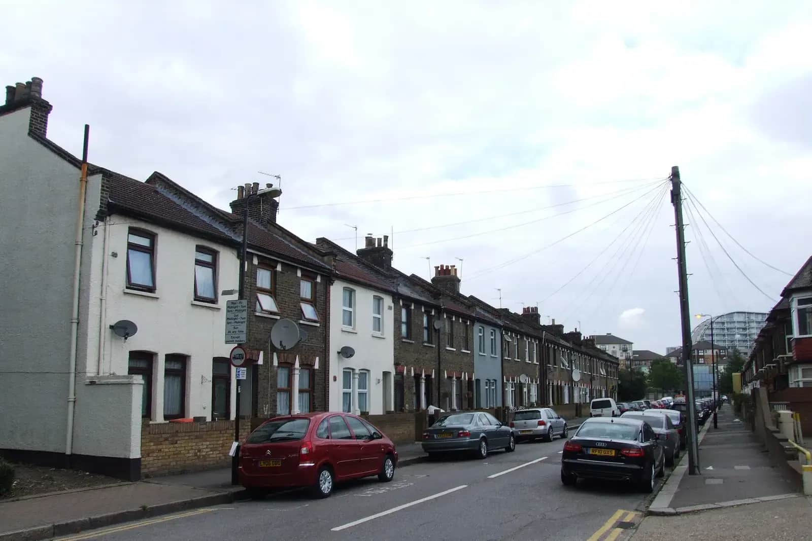 Terraced houses on Boxley Street in Silvertown, brick and painted white, with tiled roofs and a tall tower block beyond