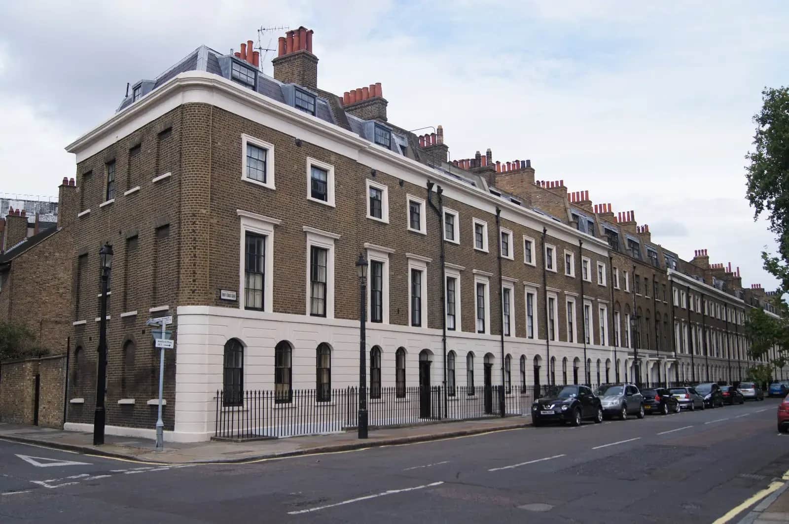 Long terrace of Georgian town houses with white stucco ground floor and brown brick above, on Trinity Street in Southwark